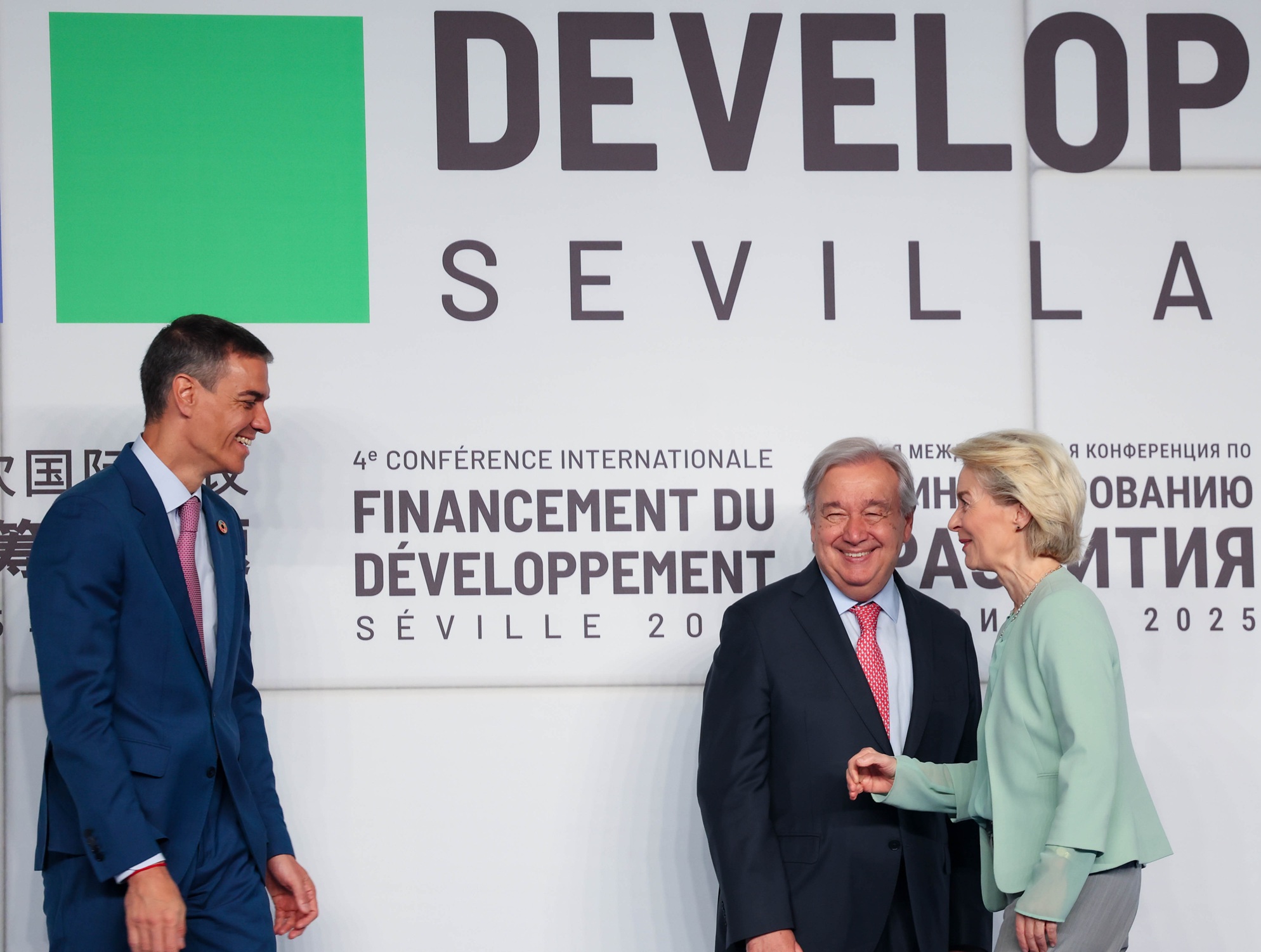 Spaniens Ministerpräsident Pedro Sánchez geht auf UNO-Generalsekretär António Guterres und EU-Kommissionspräsidentin Ursula von der Leyen zu. Letztere zwei stehen dicht beisammen, alle drei lachen. Im Hintergrund ist eine grosse Plakatwand mit dem Logo der FfD4-Konferenz.
